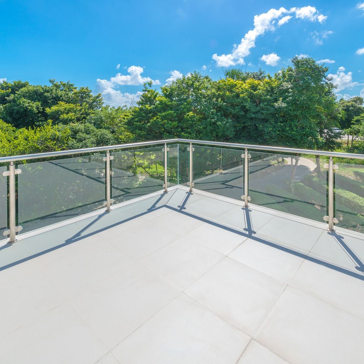 A balcony with a glass railing and trees in the background