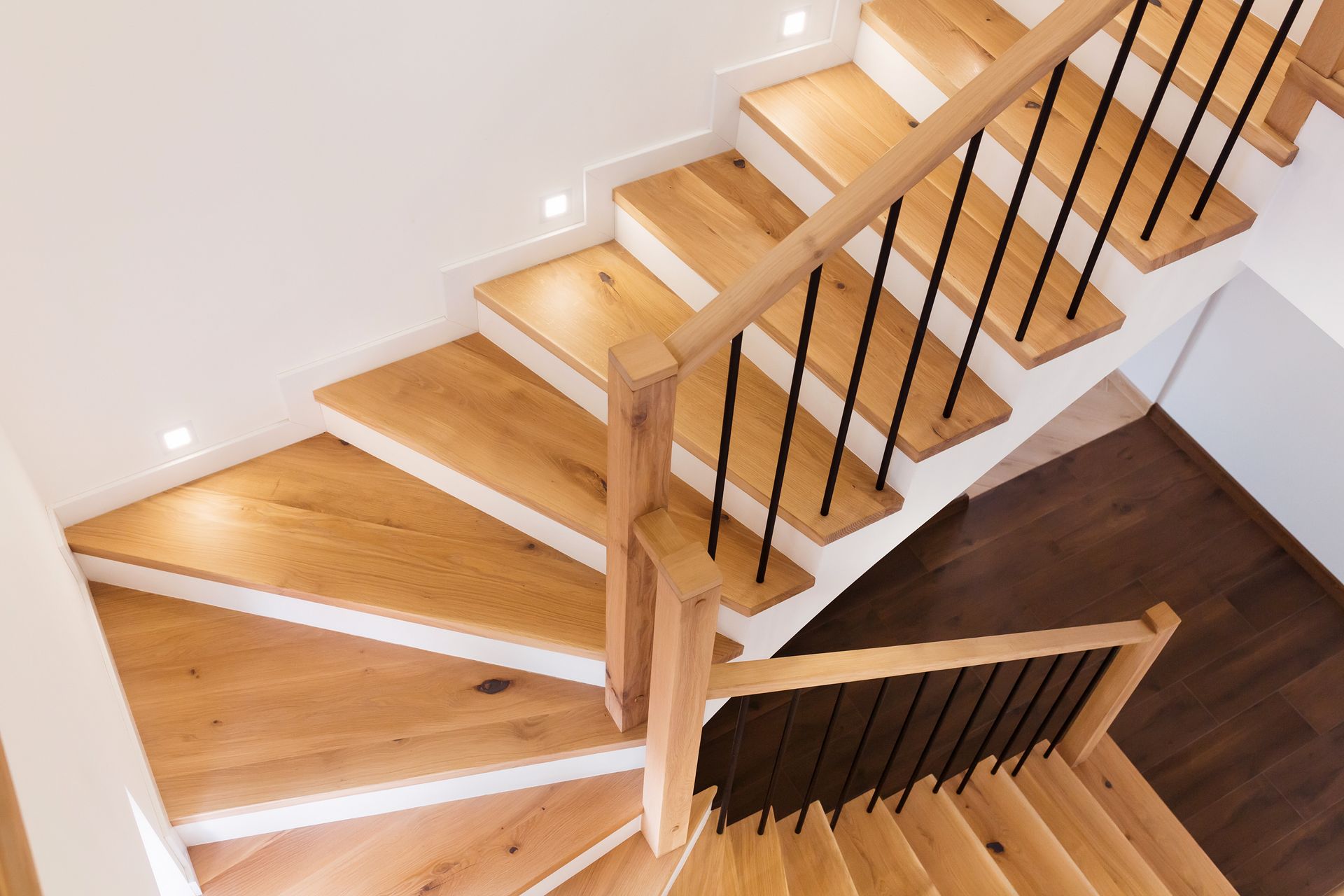 An aerial view of a wooden spiral staircase with a black railing
