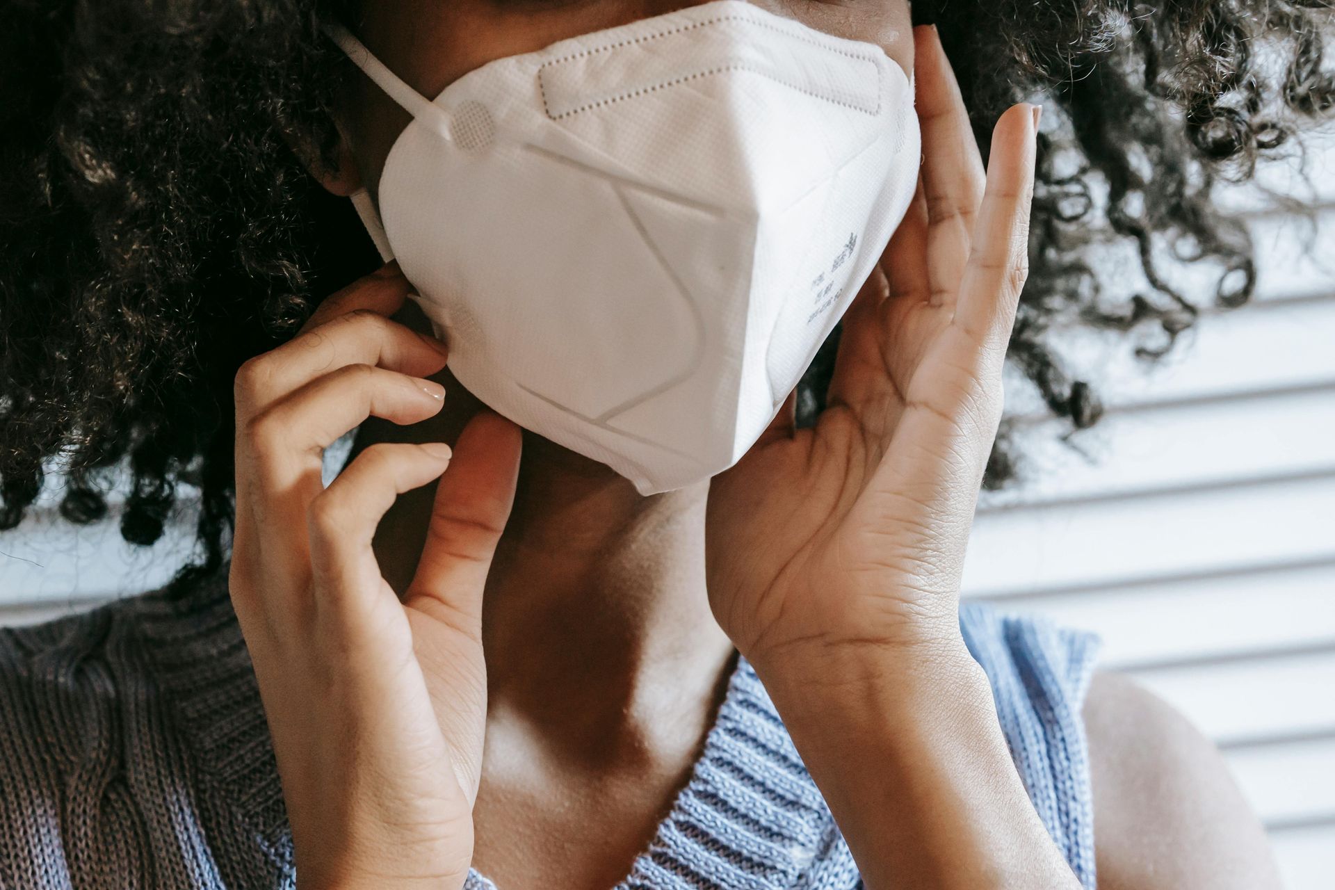 A woman wearing a mask and gloves is writing on a piece of paper.