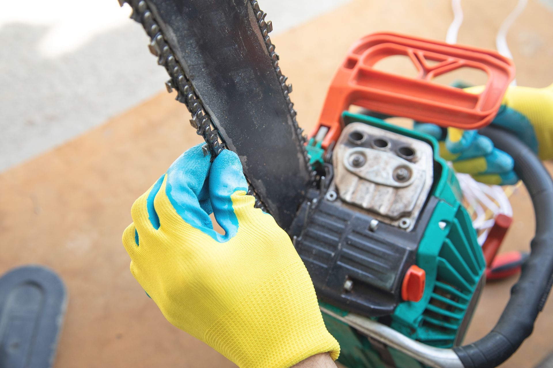 Gloved hands holding a chainsaw cutting wood outdoors