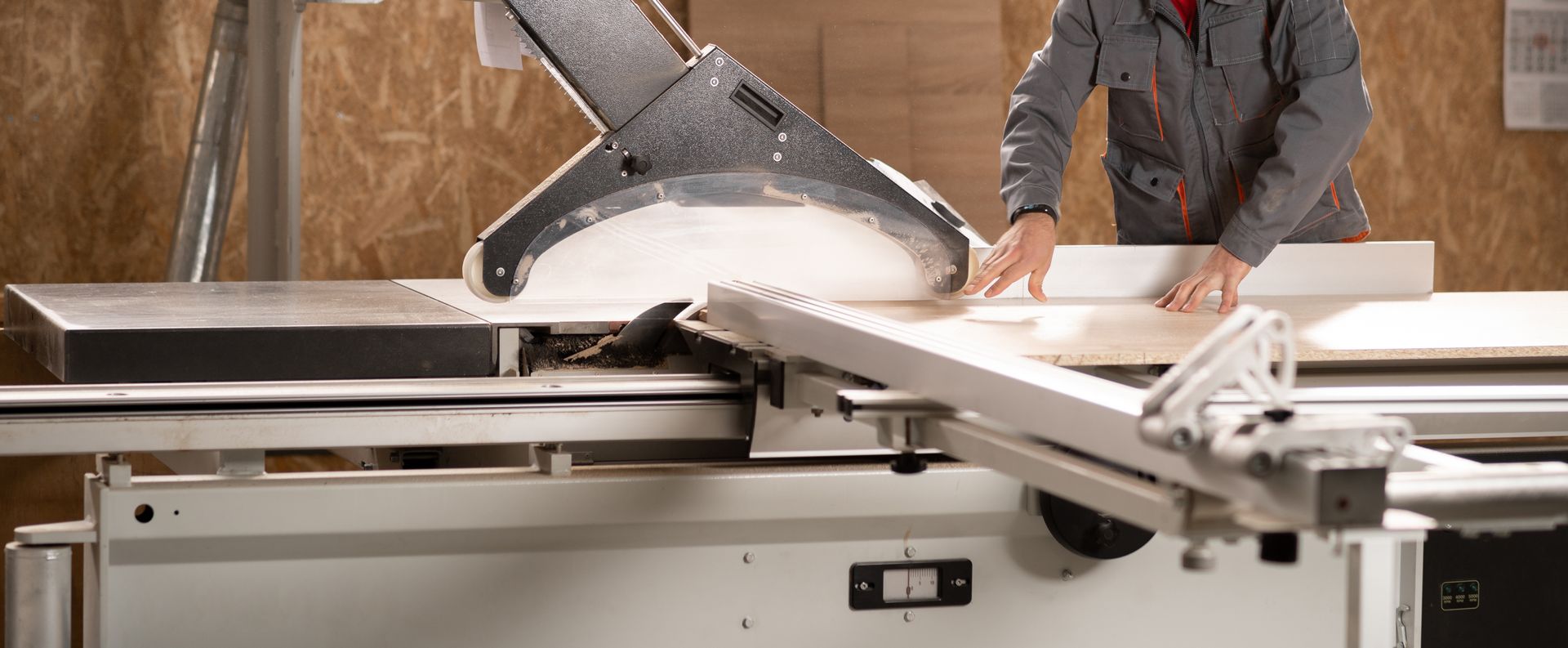 Person using a miter saw to cut a long wooden board outdoors on a workbench