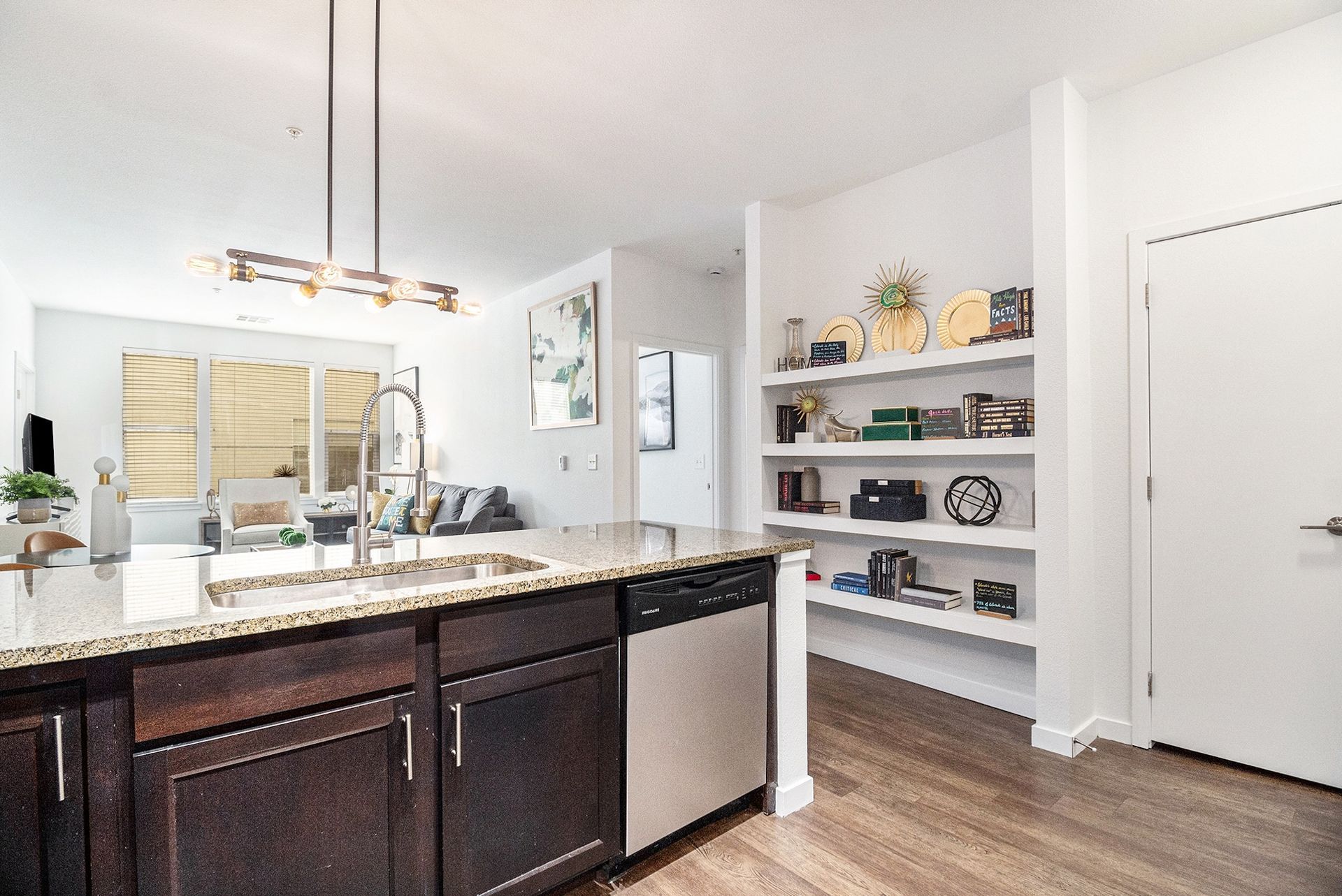 Modern kitchen with dark cabinets, white counters, open shelves, and pendant lighting