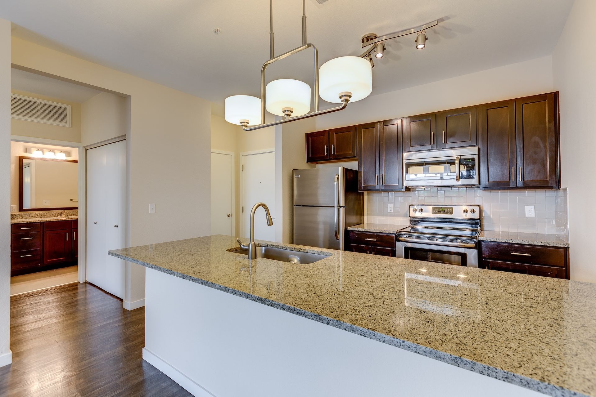 Modern kitchen with granite island, dark wood cabinets, and stainless steel appliances