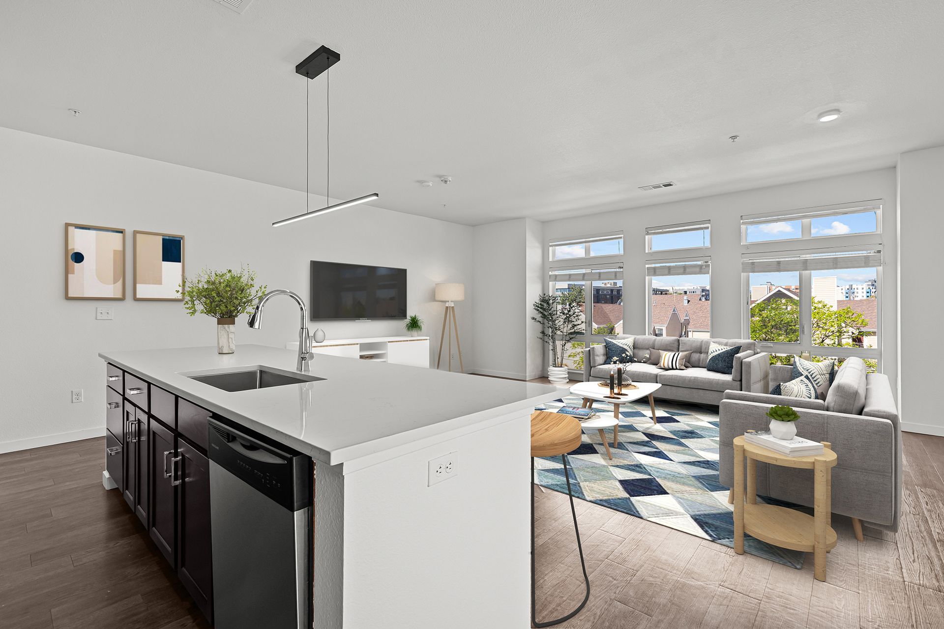 Modern living room with kitchen island, sofa, and large windows.