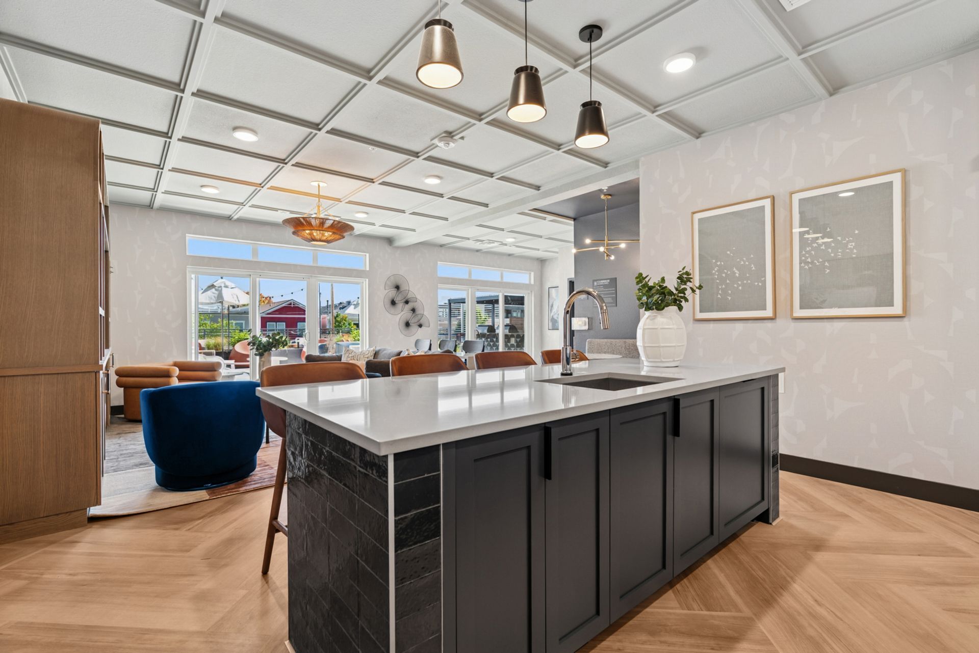 Modern kitchen with dark island, white cabinets, pendant lights, and dining area by large windows