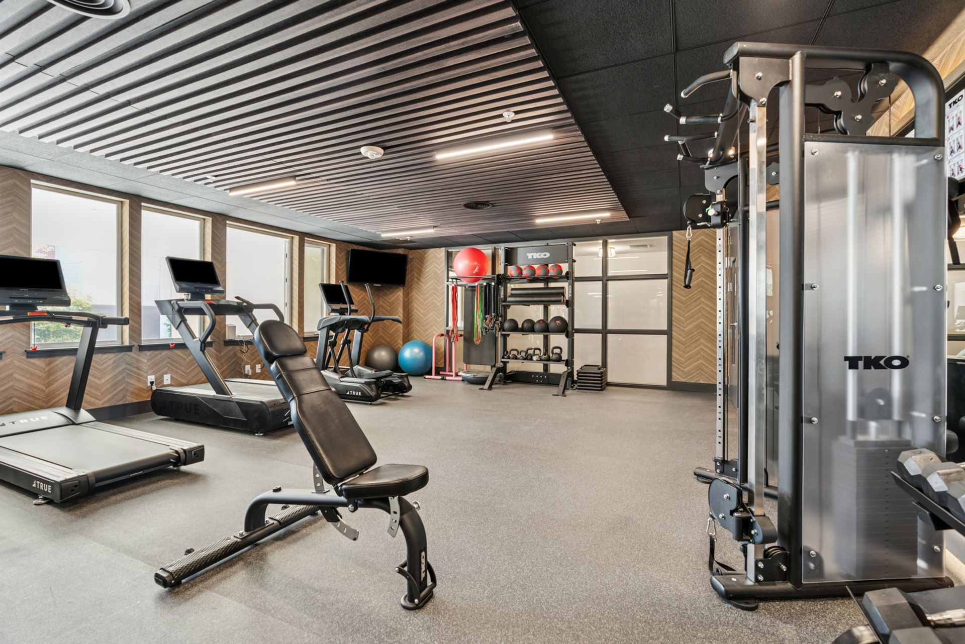 Modern gym with treadmills, weight machine, bench, and exercise balls in a spacious room