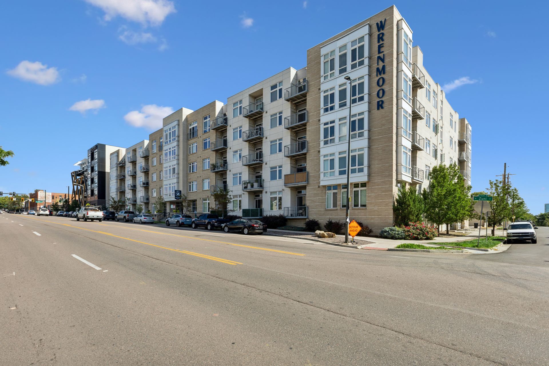 Modern apartment building along a wide street under a blue sky