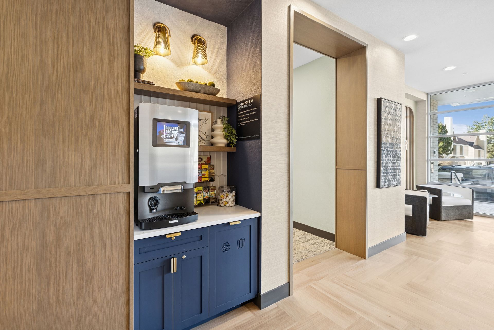 Modern apartment hallway with blue coffee station and bright living room beyond