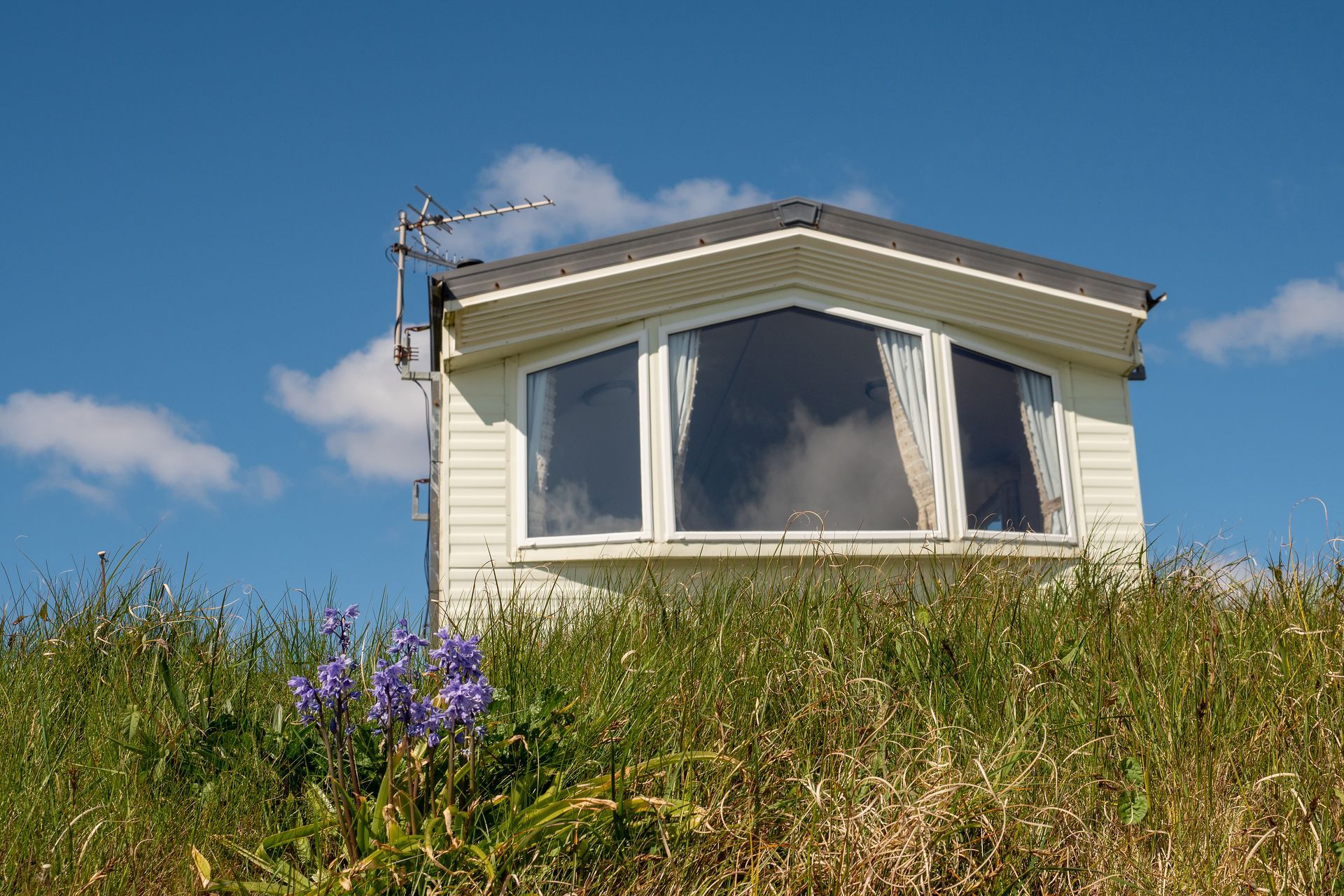 White park home on a grassy slope under a blue sky.