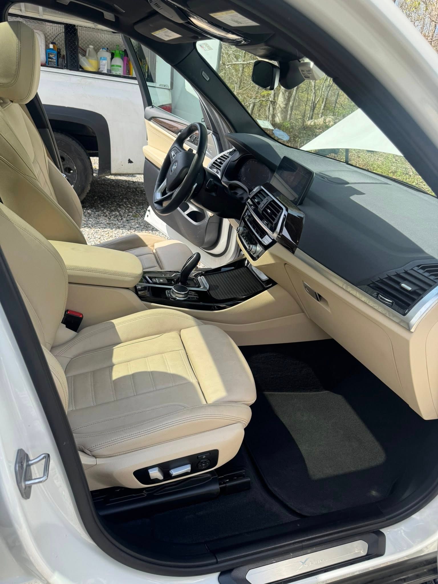 Interior view of a white SUV with tan leather seats, black dashboard, steering wheel, and floor mats.