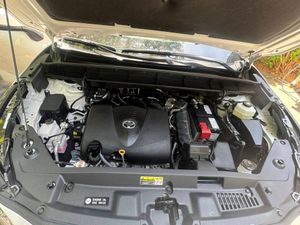 Clean engine bay of a modern Toyota vehicle with a visible engine cover, battery, and fluid reservoirs under an open hood.