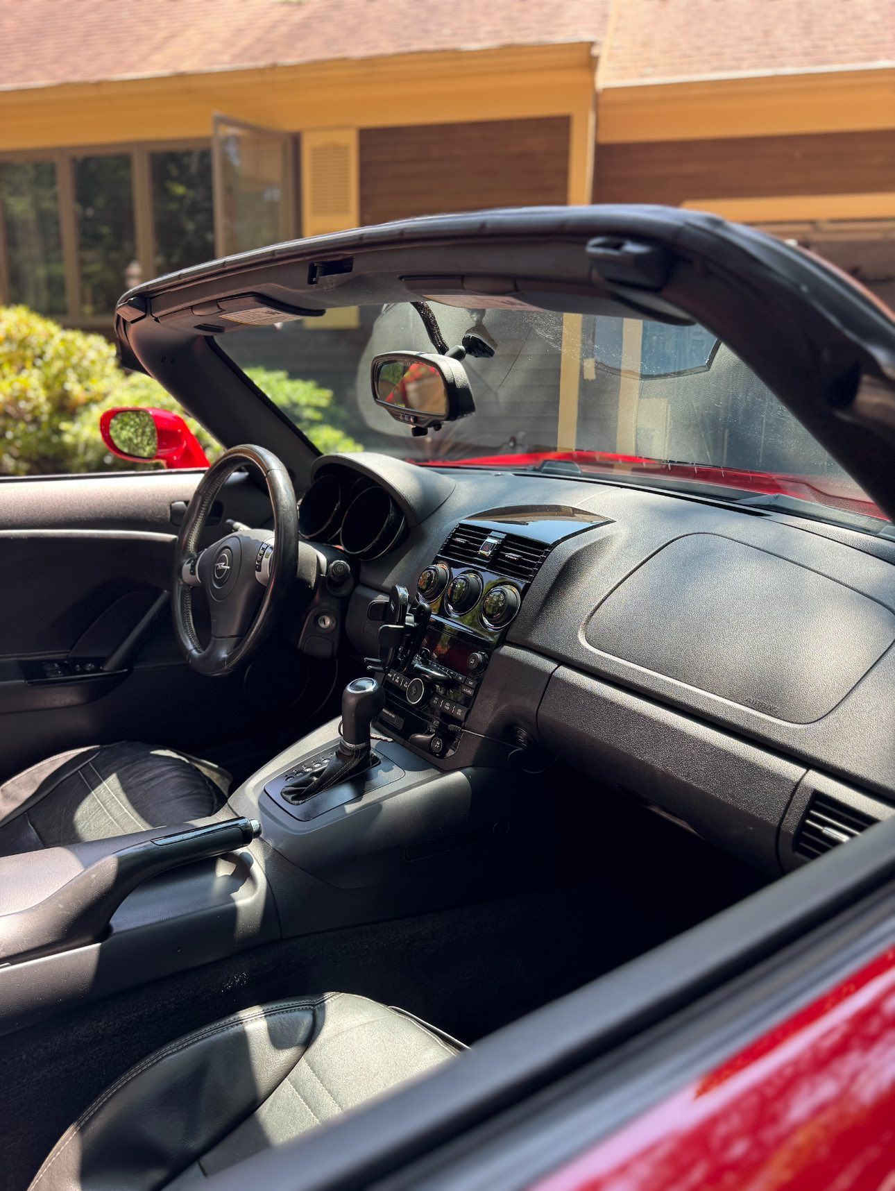 Interior of a red convertible car showing the dashboard, steering wheel, and seats from the driver's side perspective.