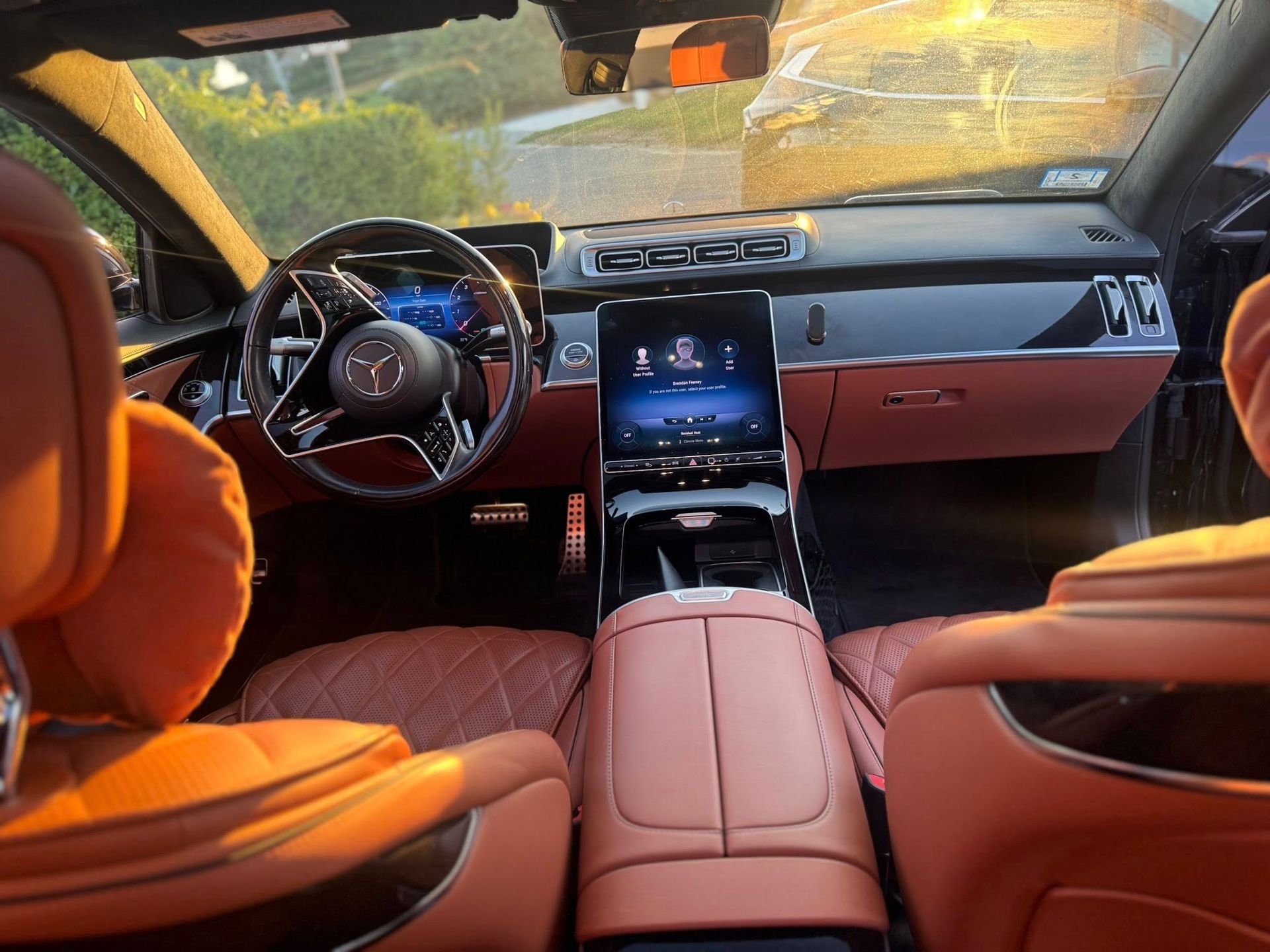 Interior view of a luxury Mercedes-Benz with orange quilted leather seats and a large touchscreen infotainment system.