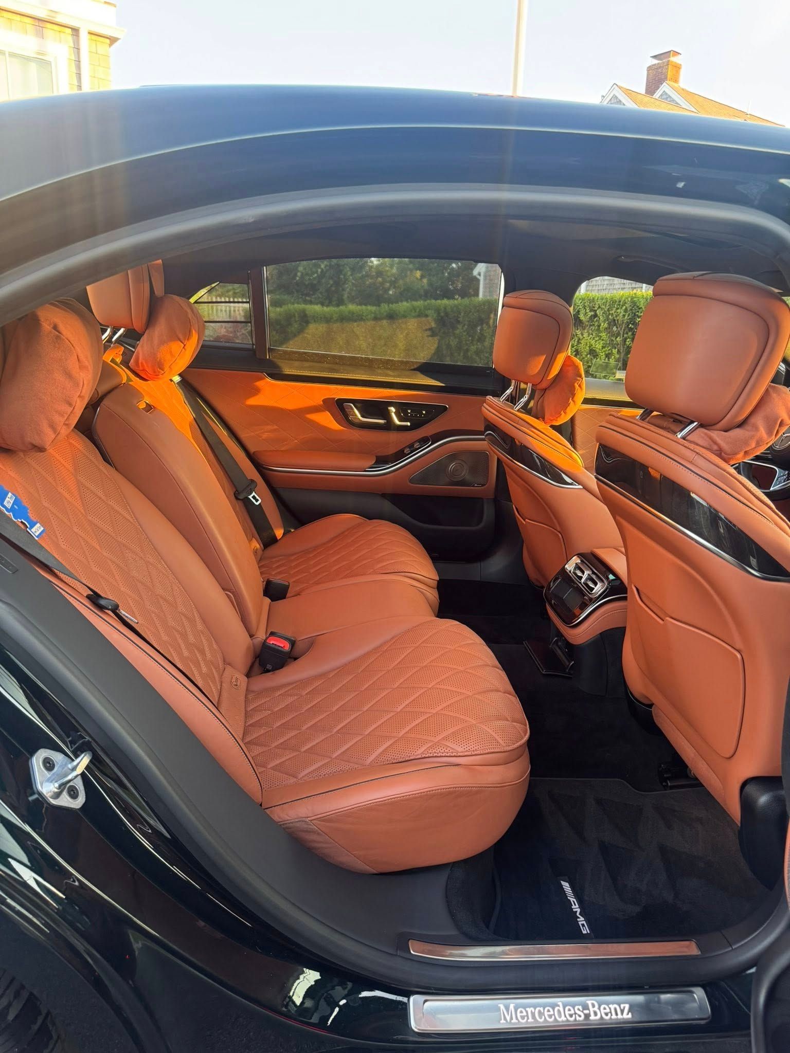 Interior view of a luxury car with tan quilted leather seats and black trim, viewed from an open passenger side door.