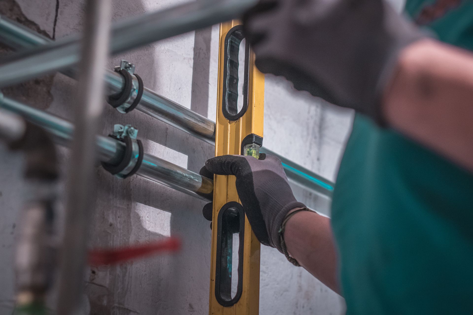 A person using water level to align water pipes for plumbing while constructing a house.