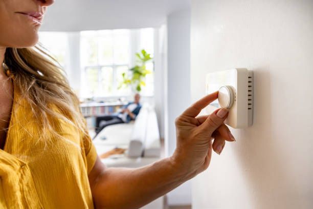 Woman adjusting thermostat