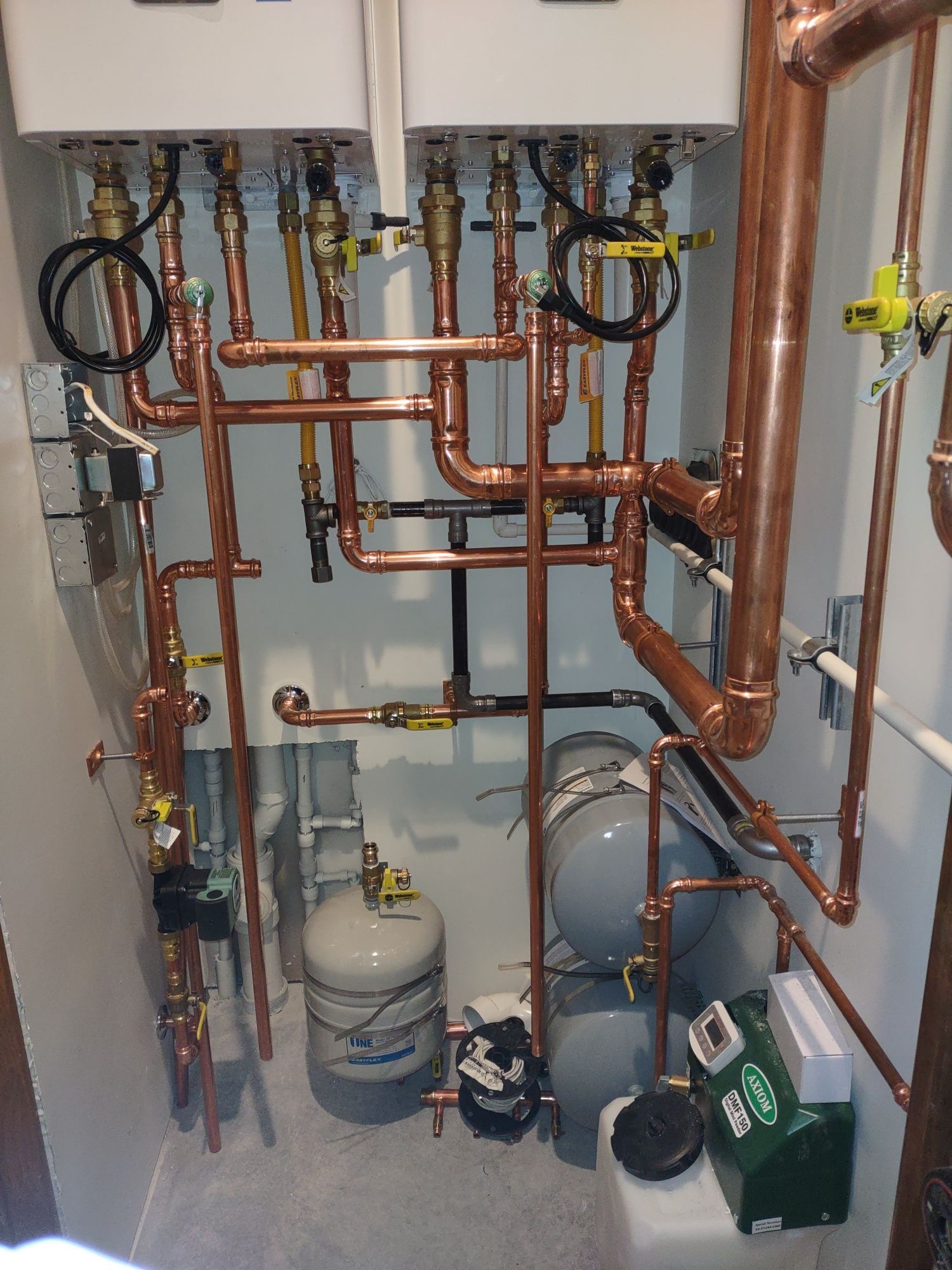 Wall of copper pipes, valves, and gas cylinders in a mechanical room.