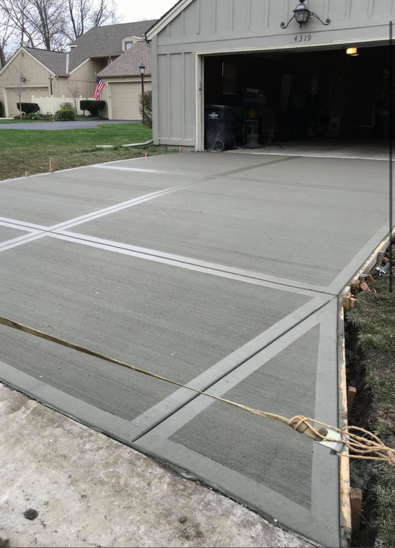 Residential driveway with large concrete slab sections and an open garage in the background