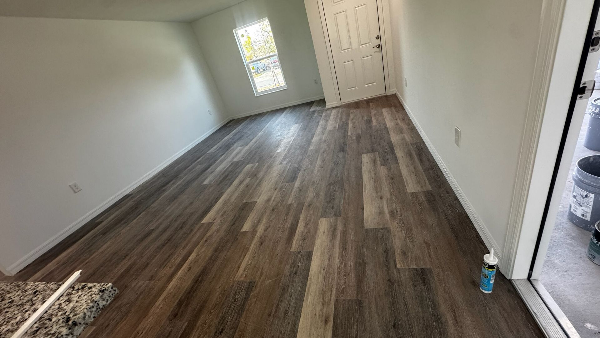 Empty room with wood-look flooring, white walls, a window, and a closet door.