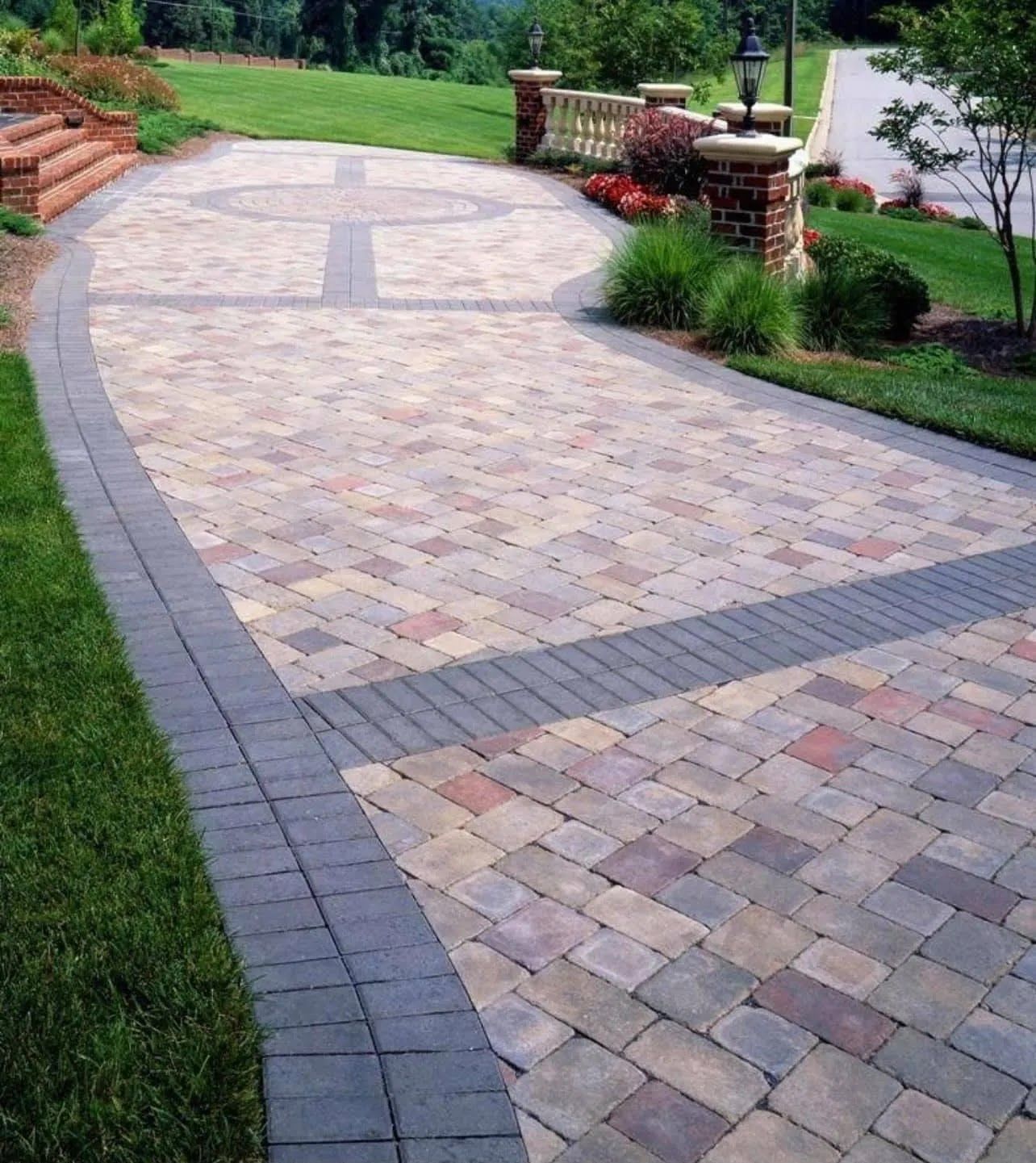Curved stone-paver walkway bordered by grass and shrubs in a landscaped yard