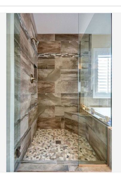 Modern walk-in shower with glass door, stone tile walls, and pebble mosaic floor