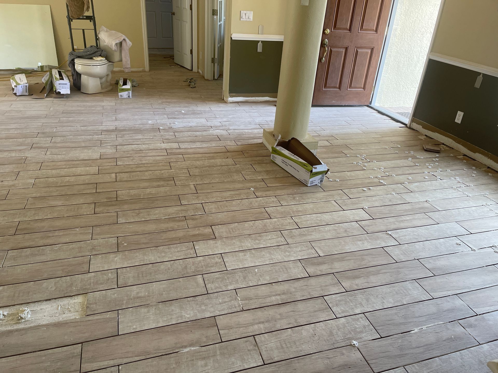 Renovation room with stripped wooden floorboards, scattered tools, and an open brown door