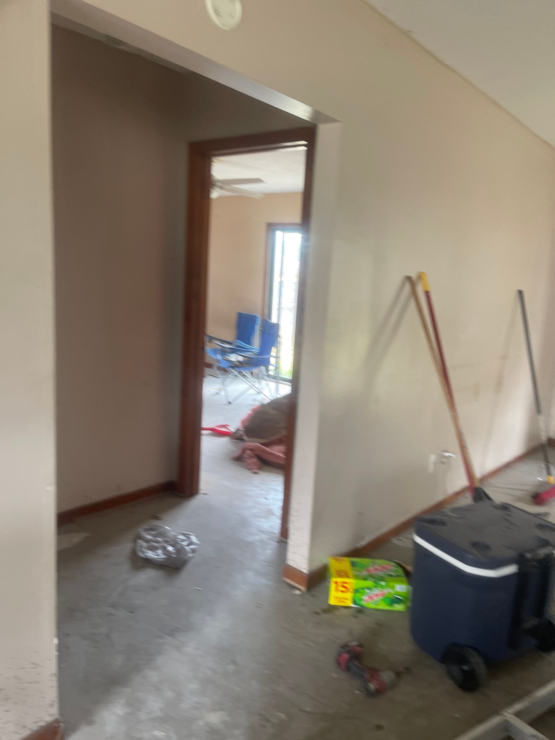 Renovation clutter in a hallway with tools, buckets, and debris on the floor near an open doorway.
