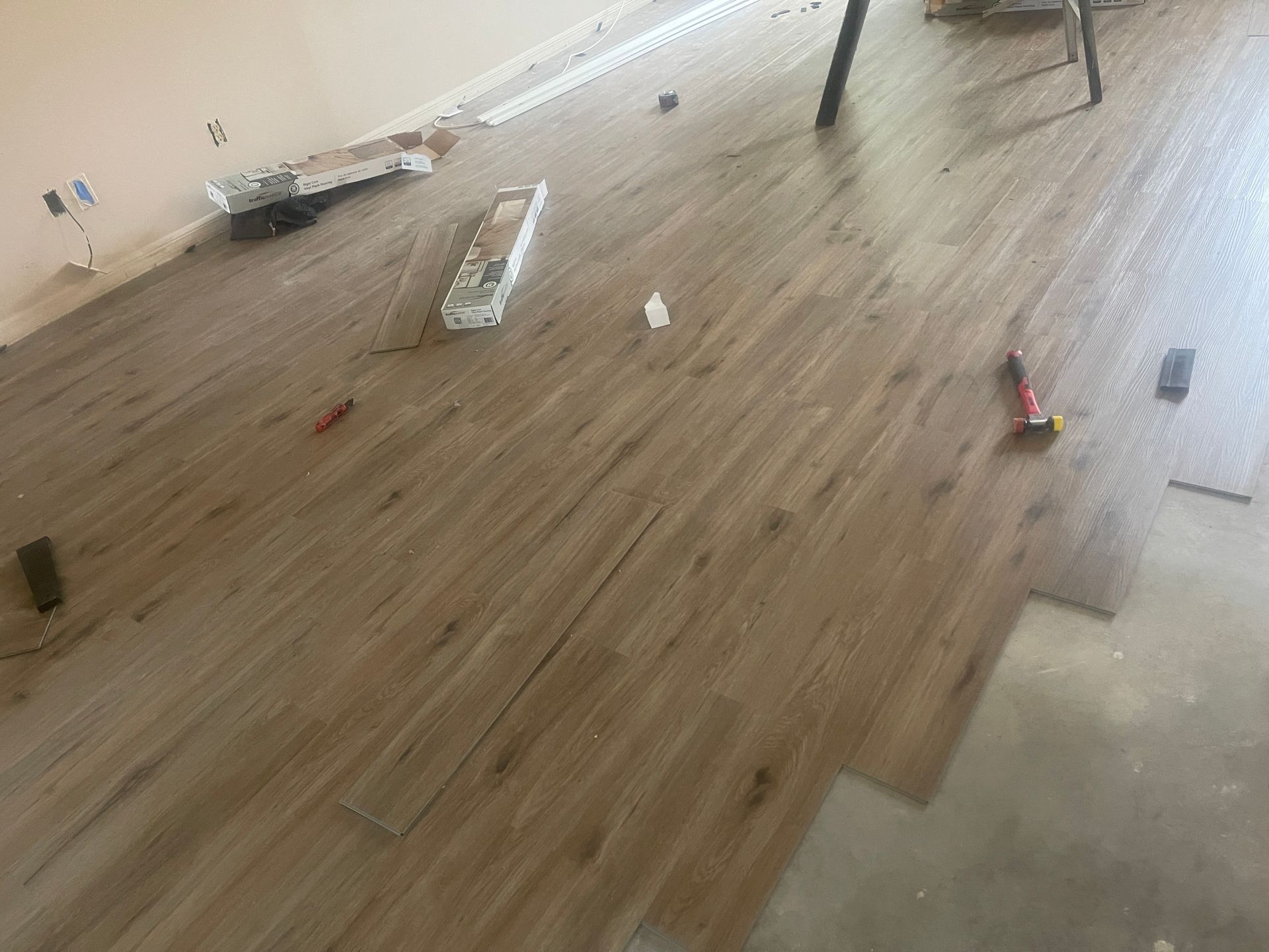 Scattered debris on a wood floor in a mostly empty room with unfinished concrete along one side
