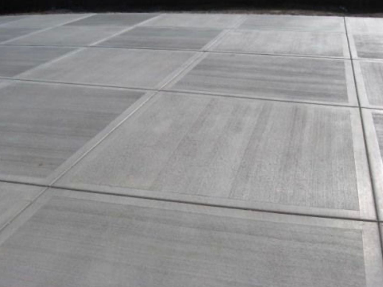 Empty concrete pavement with expansion joints and faint tire marks