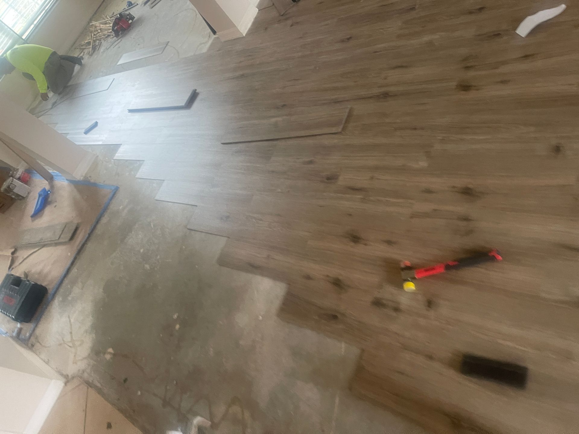 Wooden floor with scattered tools and debris in a partially renovated room.