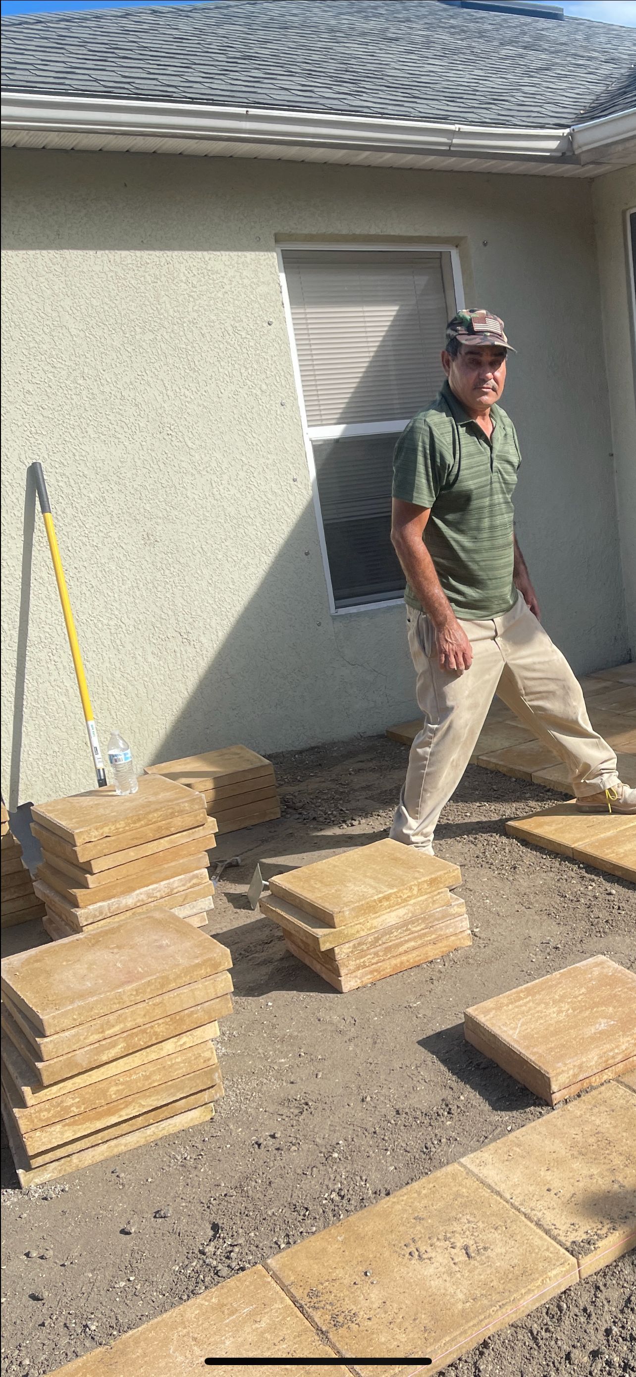 Person walking beside stacks of lumber outside a stucco house