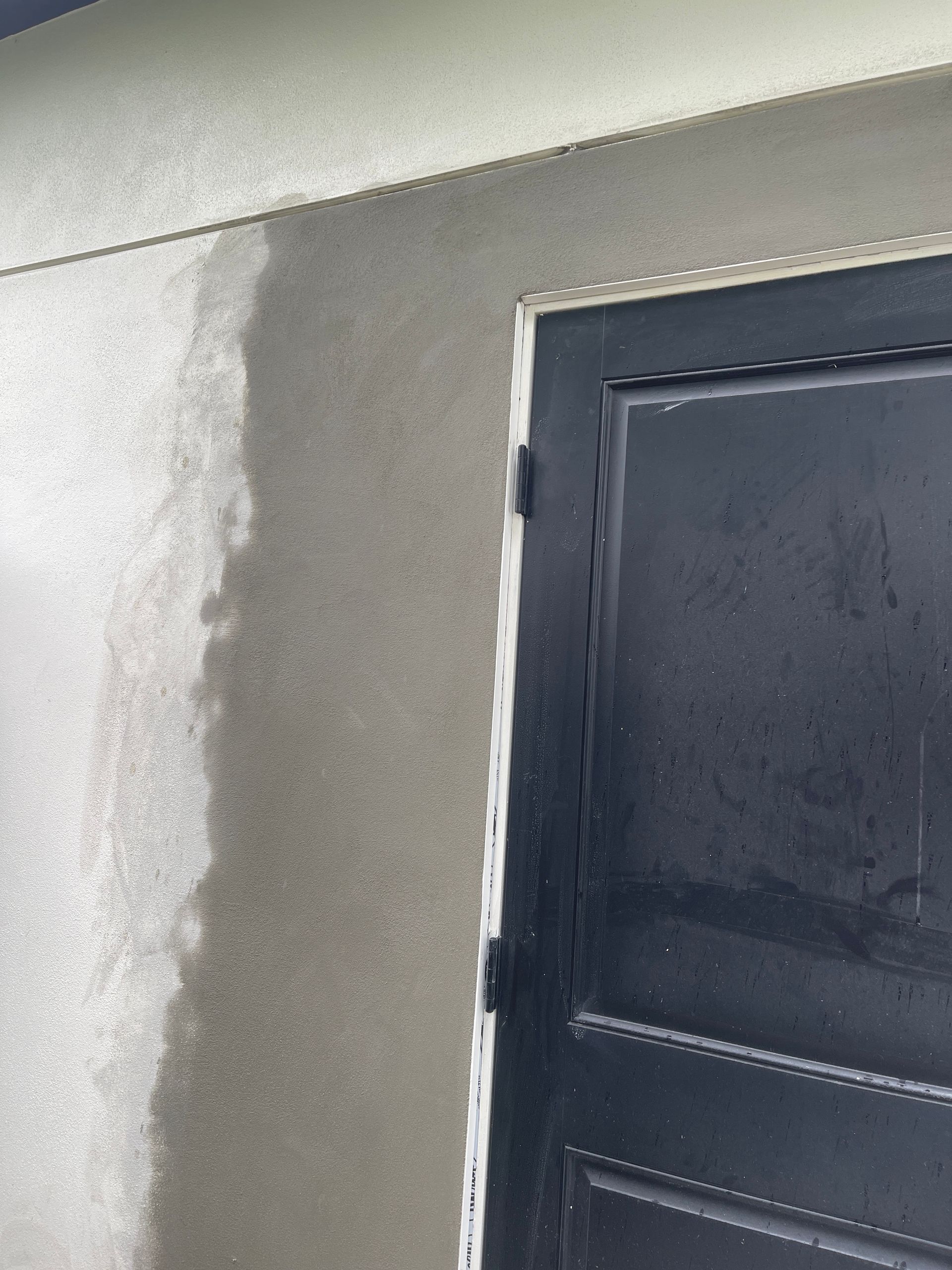 Partially painted wall beside a black door frame with visible patchy texture