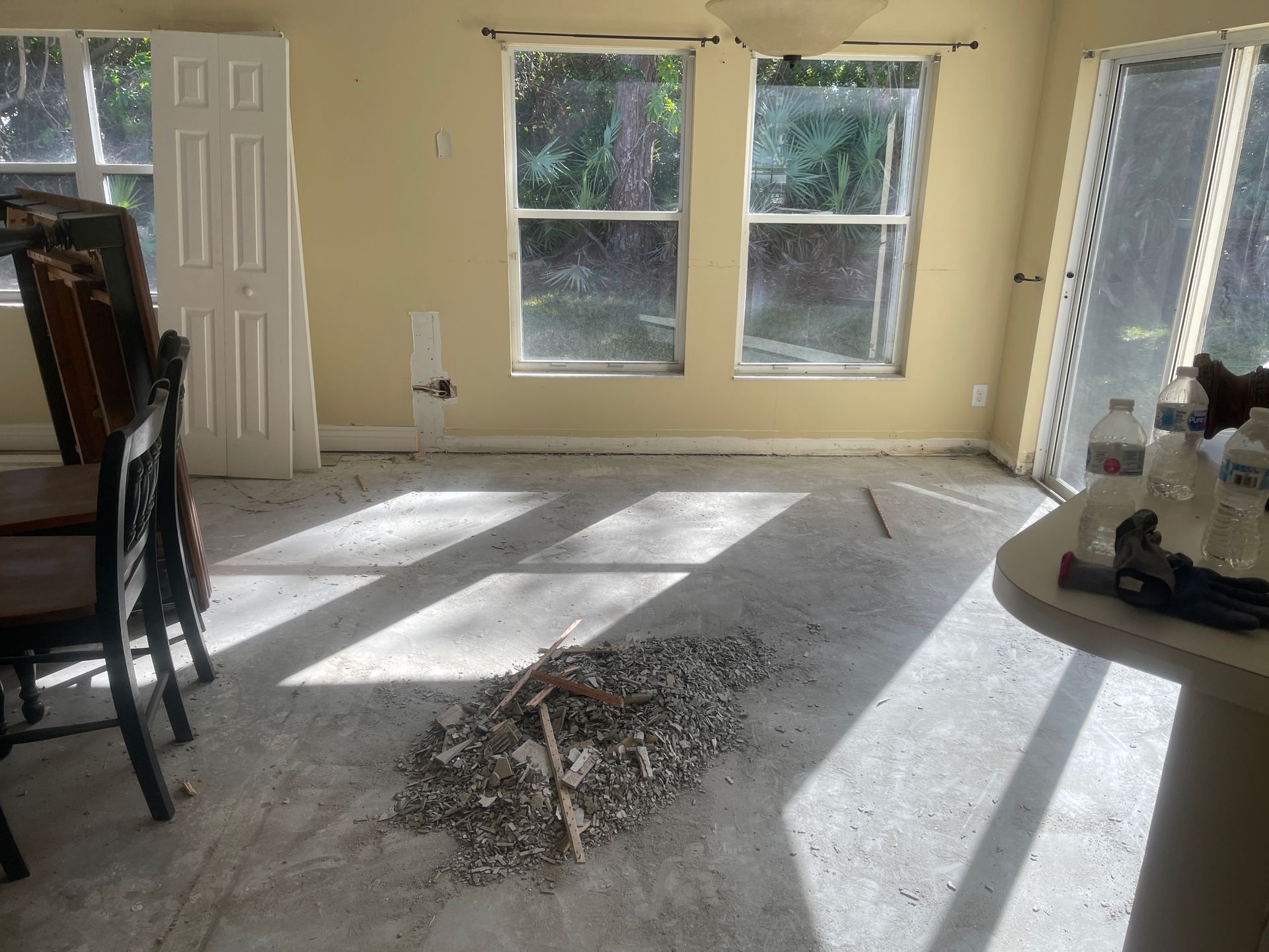 Empty living room with sunlight on bare floor and a pile of debris in the center