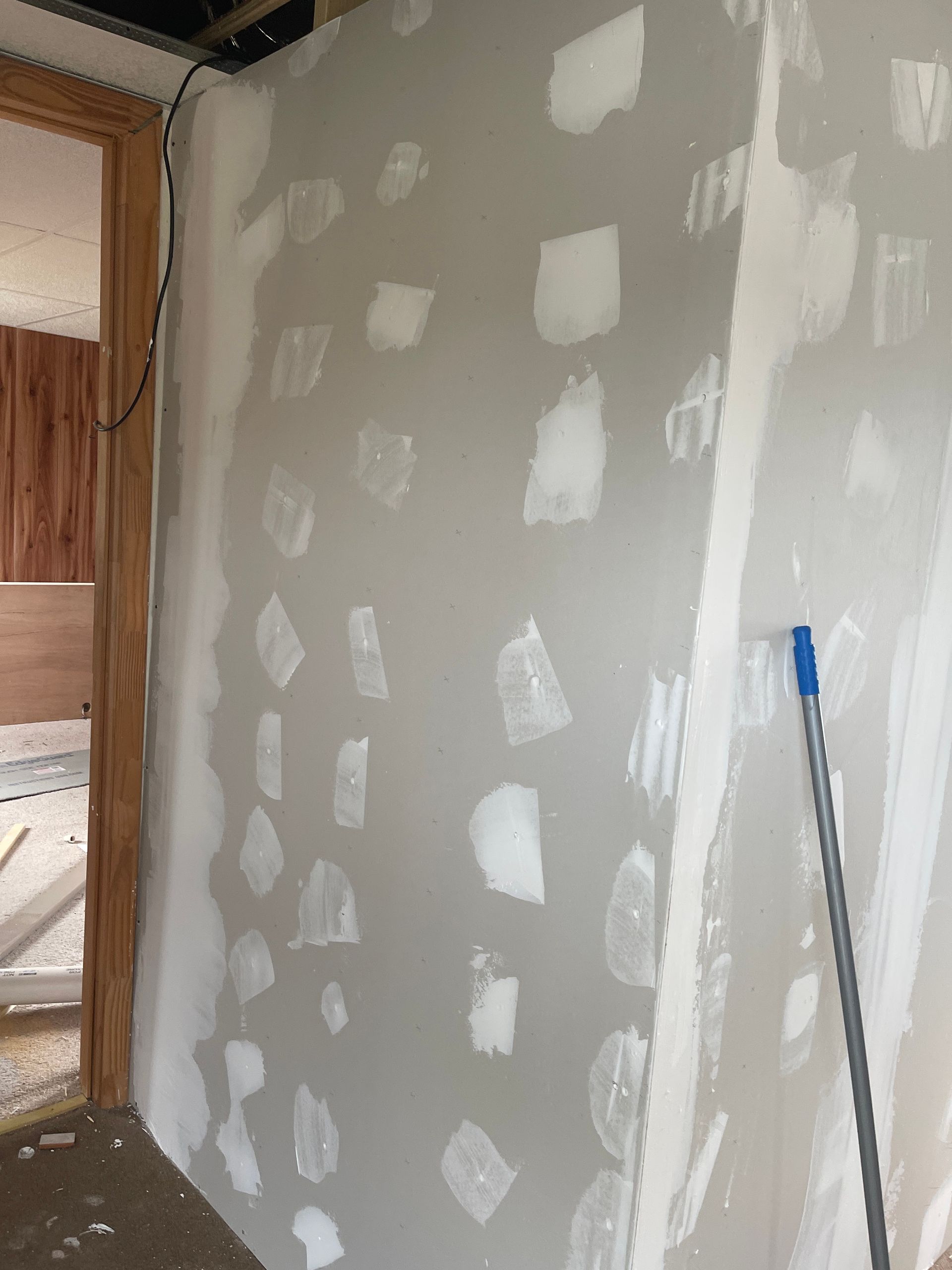 Partially finished drywall wall with white patch spots in a construction interior