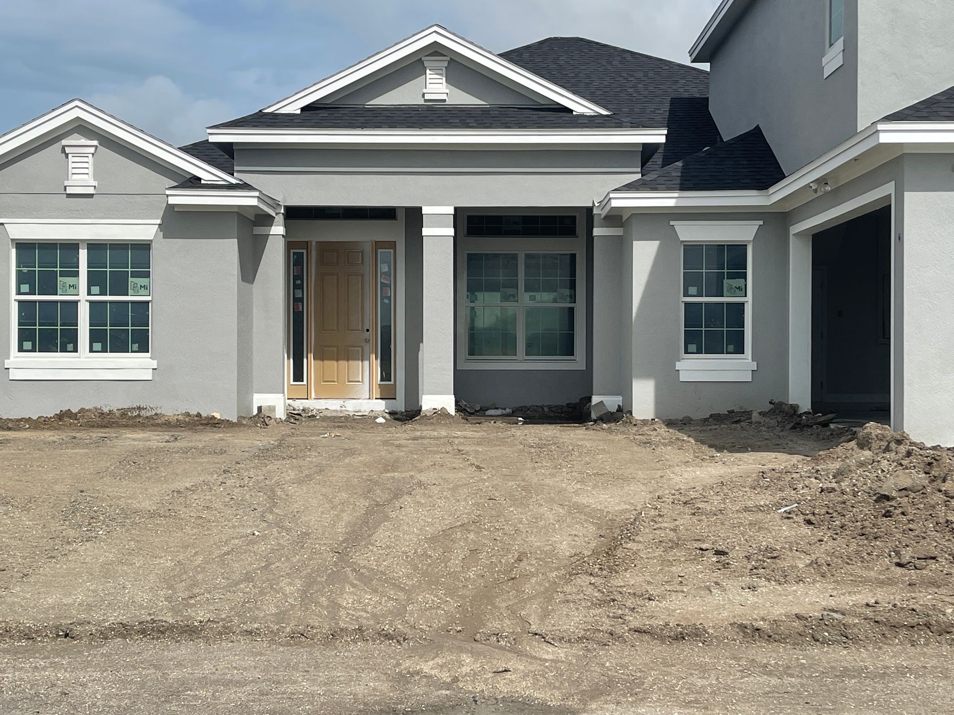 New gray house under construction with unfinished dirt front yard and front porch