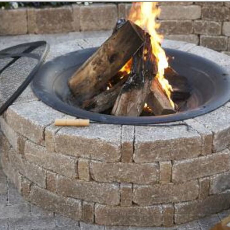 Stone fire pit with burning logs and flames outdoors