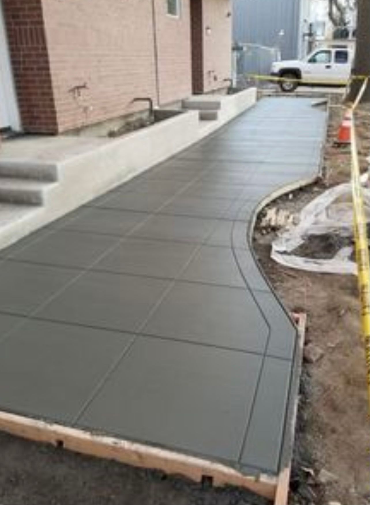 Freshly poured dark gray concrete walkway beside a building, under construction.