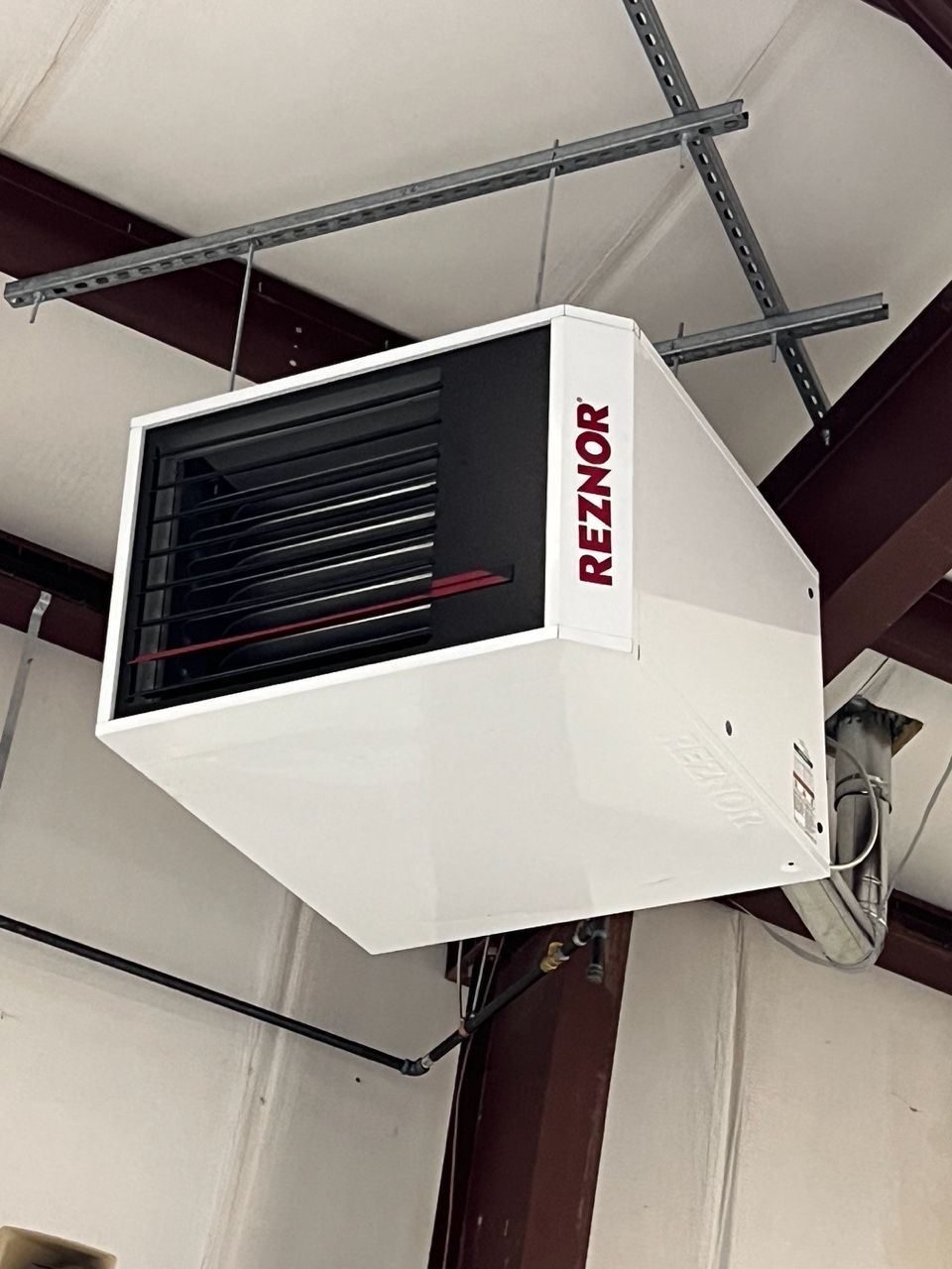 A white Reznor unit heater suspended from the ceiling in a workshop setting.