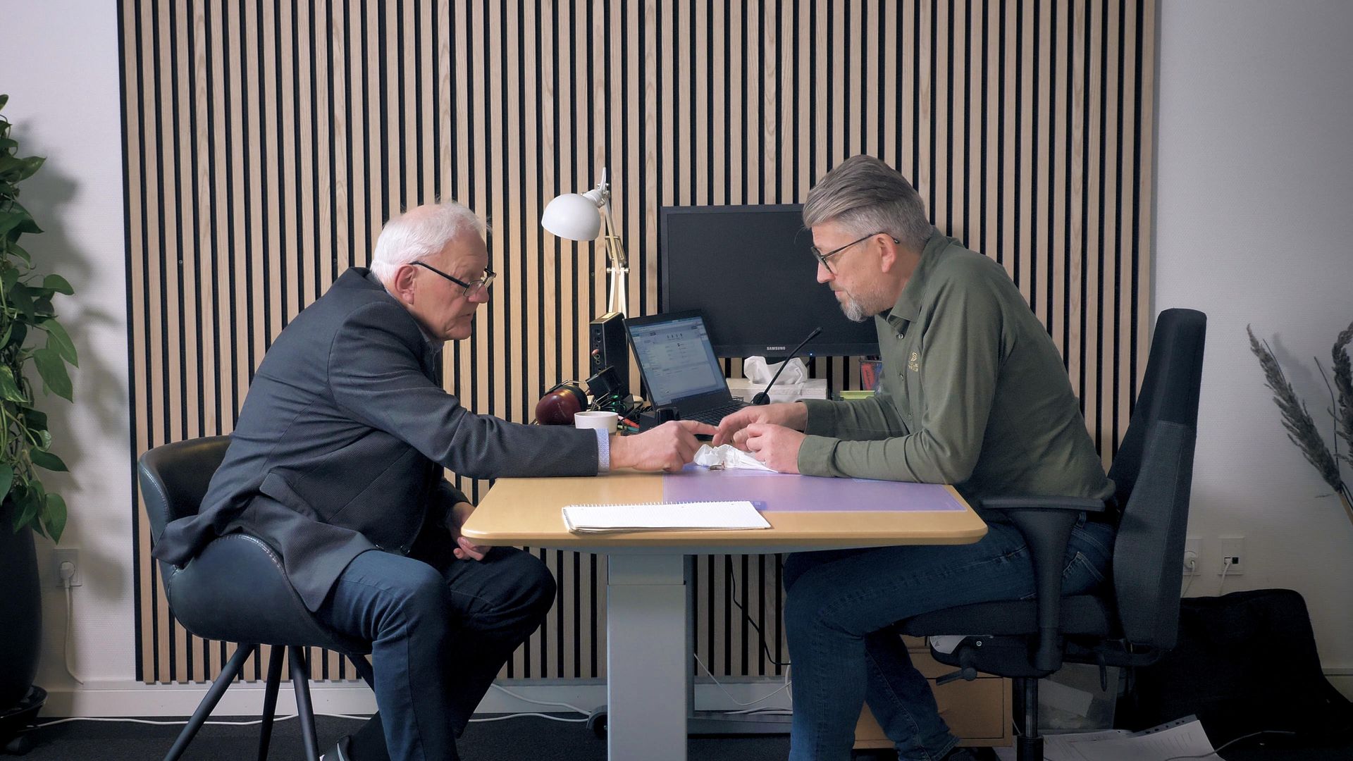 To mænd sidder ved et bord og taler med hinanden.
