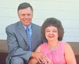 a man in a suit and tie is sitting next to a woman in a pink shirt .