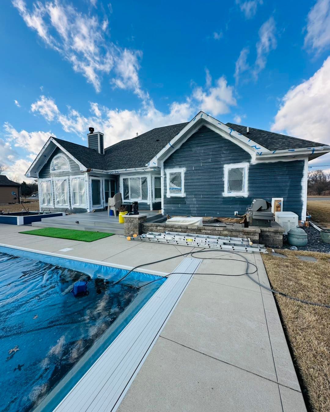 Gray house with a swimming pool and patio under a blue sky