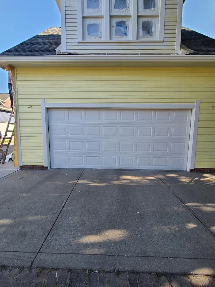Yellow house exterior with white garage door and concrete driveway under blue sky