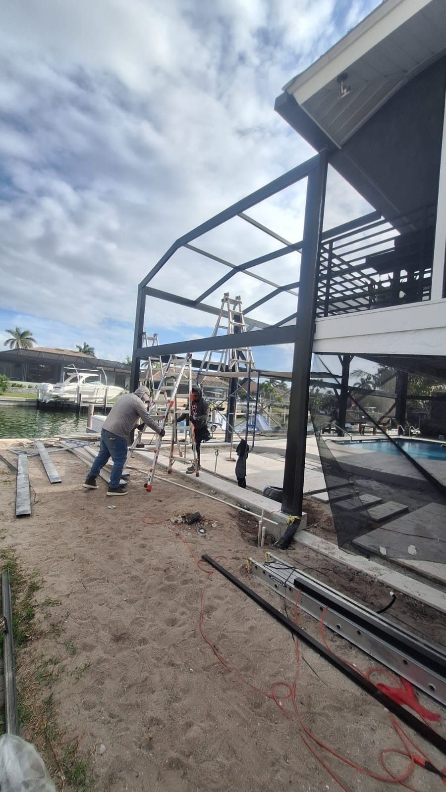 A group of men are working on a house next to a pool.