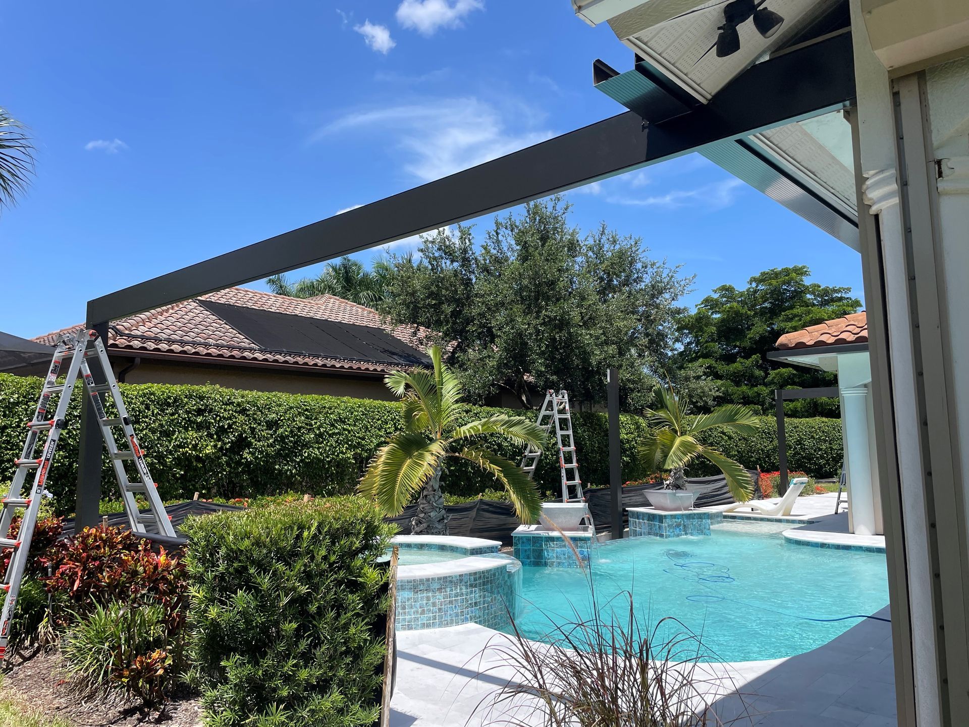 A screened in swimming pool with palm trees in the background