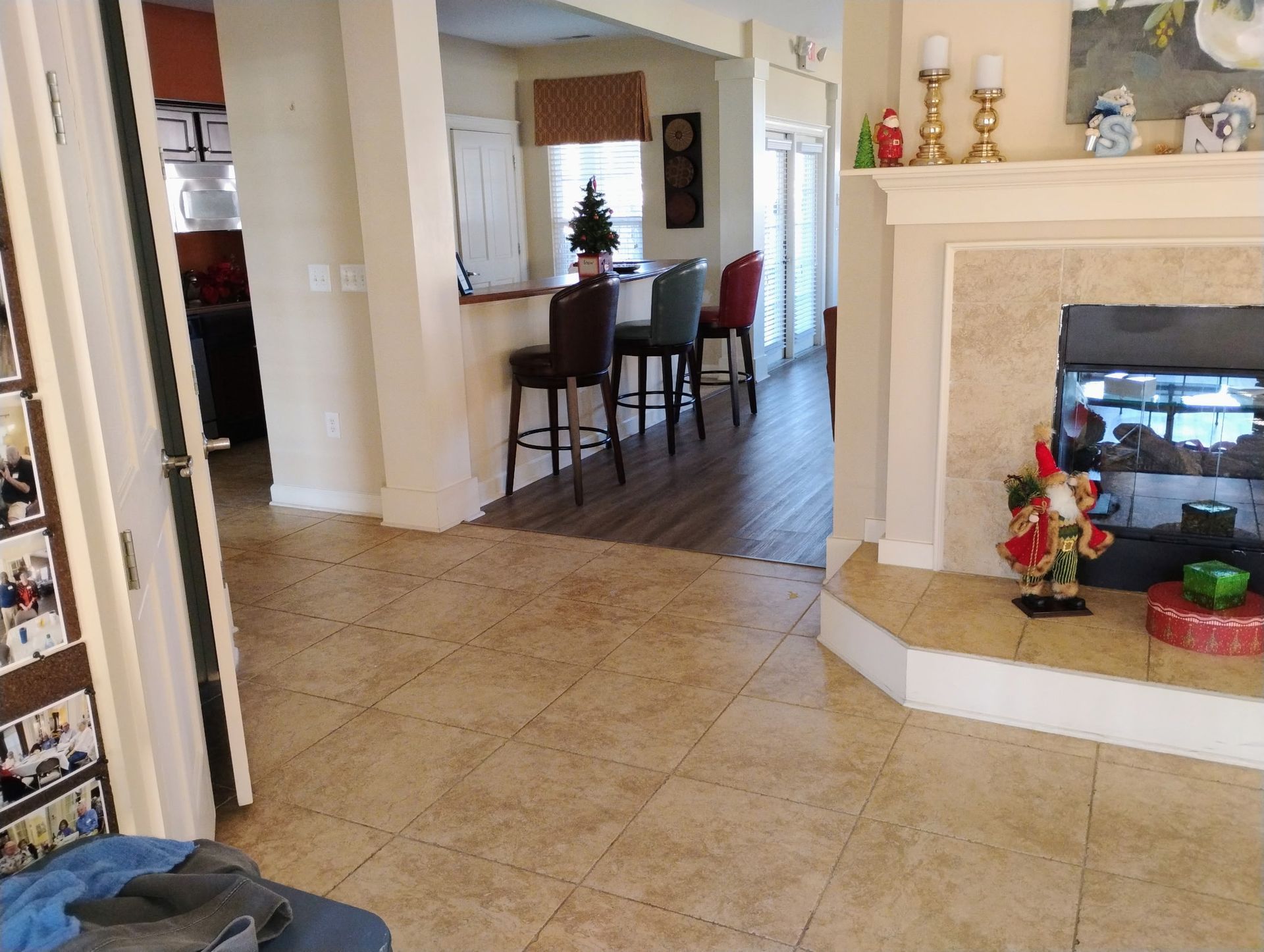 Three people cleaning a living room. A man on a step stool dusts the ceiling, while two women tidy a sofa.
