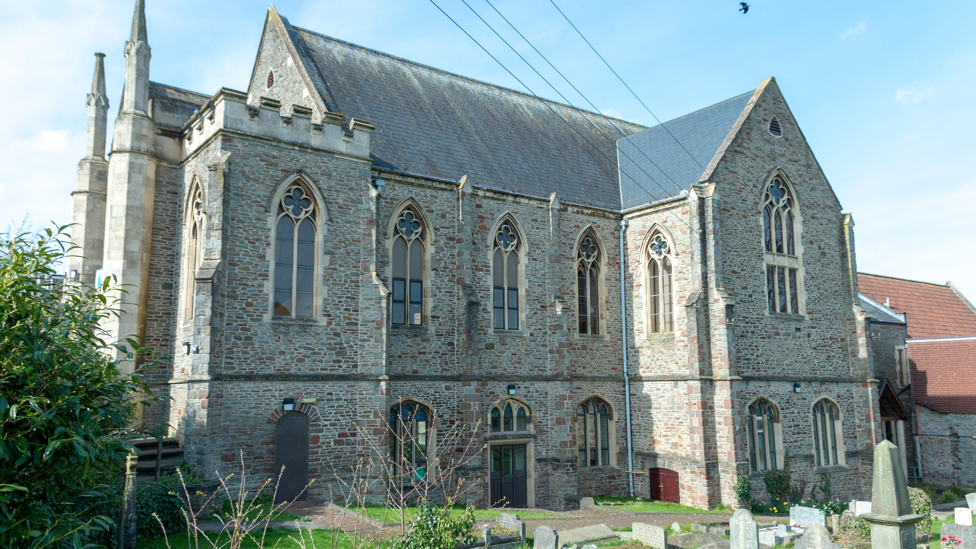 A large stone church with a cemetery in front of it.