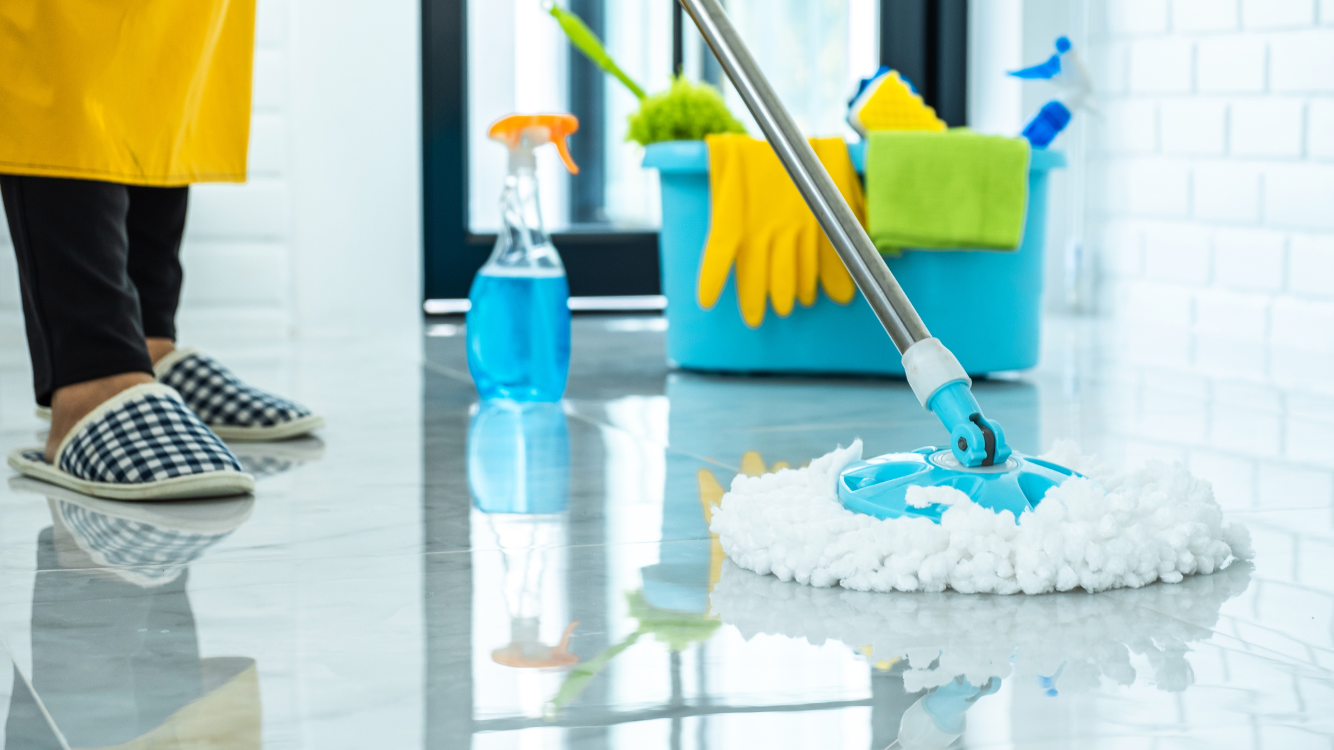 A person is holding a blue bucket filled with cleaning supplies.
