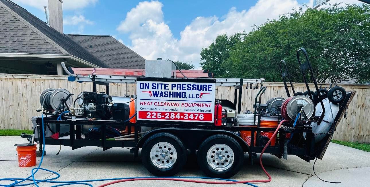 Pressure washing trailer parked on driveway, with equipment, hoses, and signage for 