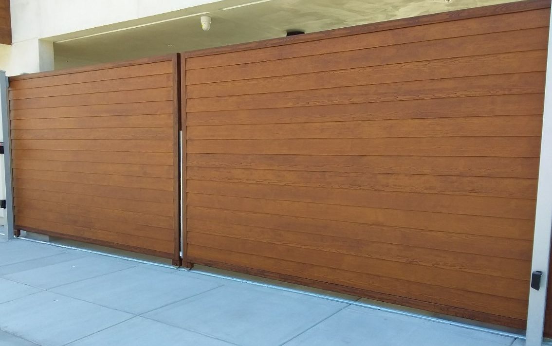 Two large wooden garage doors on a beige building beside a tiled walkway.