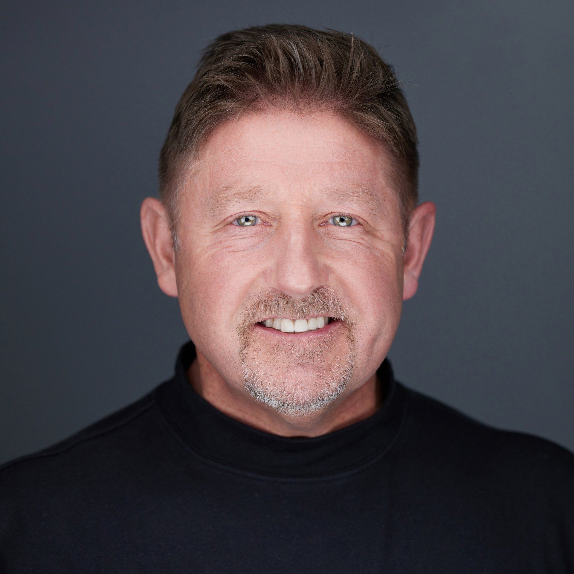 A man with a beard and mustache is smiling for the camera.